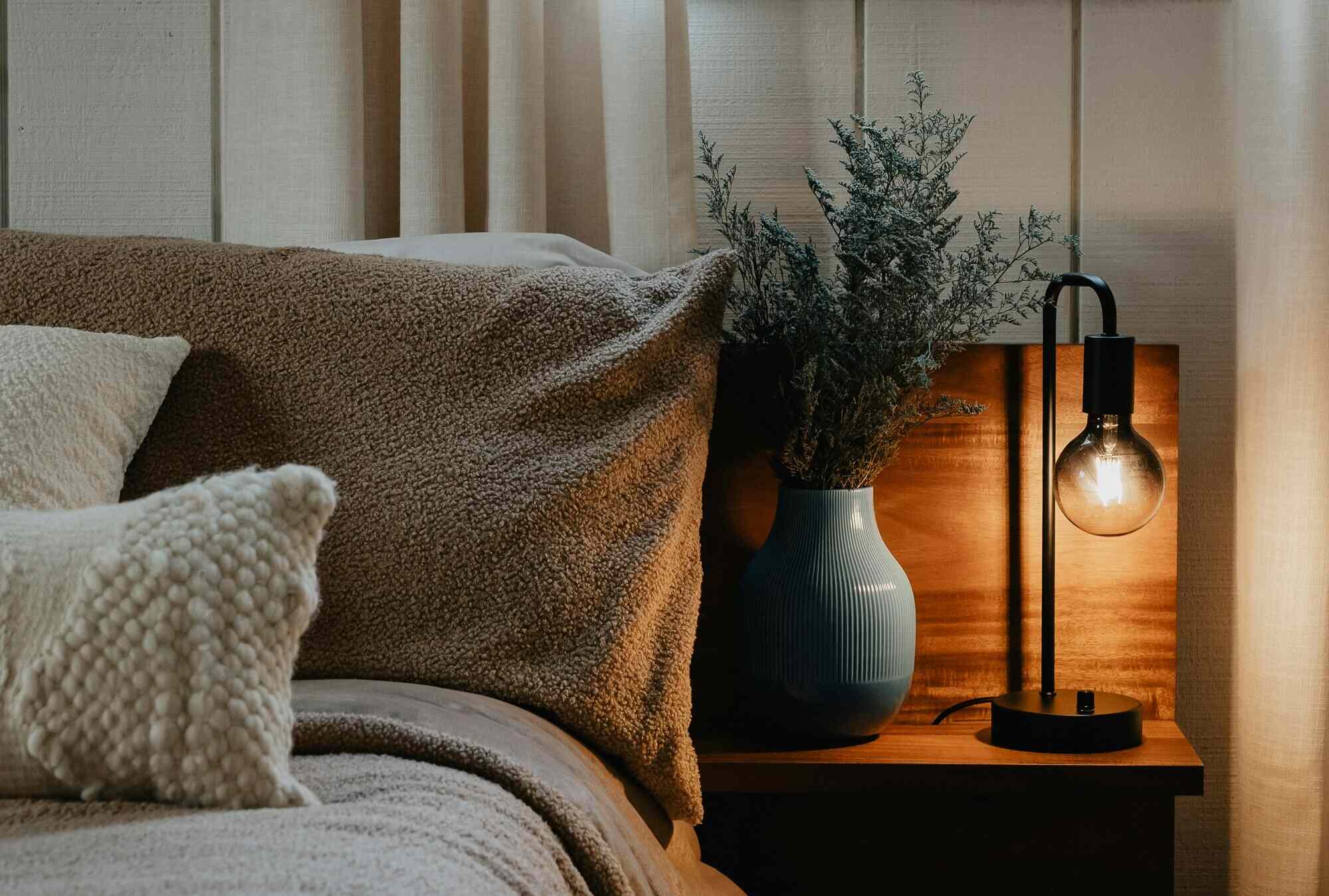 A softly lit bedside table and slightly rumpled bed at night, suggesting intentional rest and a steady, non-obsessive approach to health.